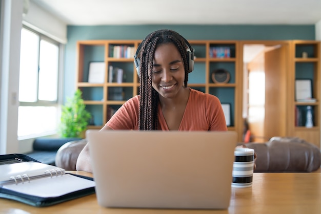 Retrato de uma mulher em uma videochamada com laptop e fones de ouvido enquanto trabalhava em casa.