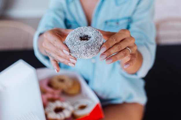 Retrato de uma mulher europeia com cabelo loiro, desfrutando de donuts na cozinha em casa villa.