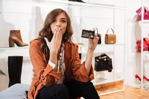 Retrato de uma mulher excitada segurando o cartão de crédito