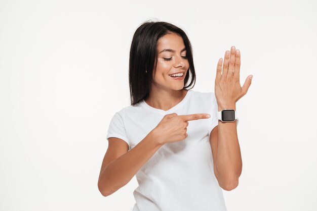 Retrato de uma mulher feliz, apontando o dedo no relógio inteligente