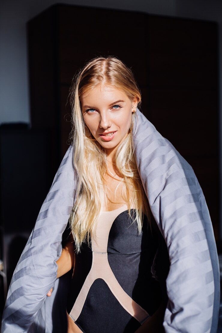 Foto grátis retrato de uma mulher feliz e calma no quarto com um cobertor cinza despojado e um corpo preto e bege, roupa de dormir em casa