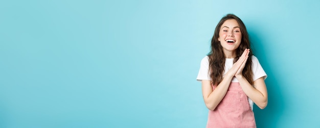 Foto grátis retrato de uma mulher feliz, regozijando-se com boas notícias, bate palmas e sorrindo agradecendo por gif