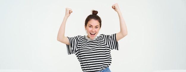 Retrato de uma mulher feliz vencendo comemorando a vitória torcendo pela equipe triunfando em pé sobre o branco