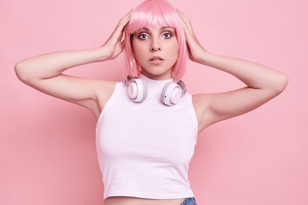 Retrato de uma mulher linda com cabelo rosa curtindo música em fones de ouvido