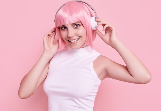 Retrato de uma mulher linda com cabelo rosa curtindo música em fones de ouvido