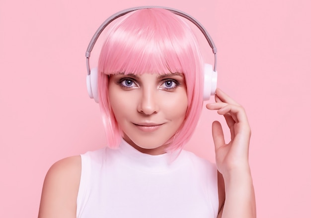 Retrato de uma mulher linda com cabelo rosa curtindo música em fones de ouvido