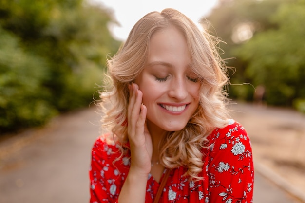 Retrato de uma mulher loira elegante e atraente sorridente, com blusa vermelha, roupa de verão e brincos sorrindo