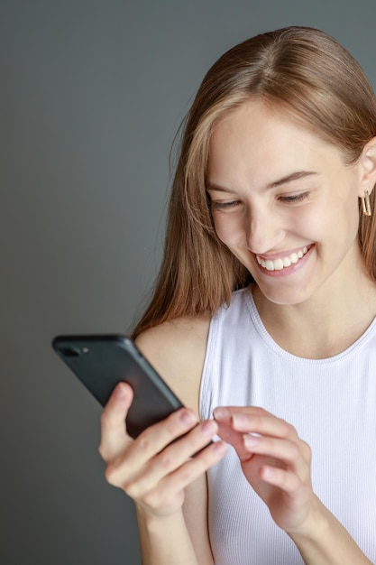 Retrato de uma mulher morena de 20 anos usando telefone celular em pé isolado sobre fundo amarelo