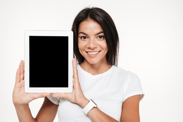 Retrato de uma mulher morena sorridente, mostrando o tablet de tela em branco