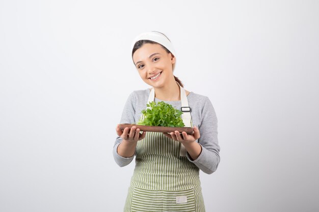 Retrato de uma mulher muito fofa segurando uma placa de madeira com salsa fresca