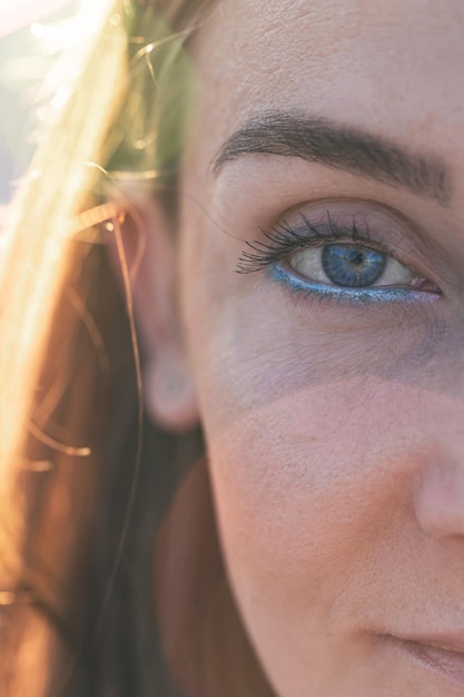 Retrato de uma mulher na praia com delineador azul em um fundo desfocado