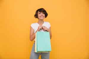 Foto grátis retrato de uma mulher satisfeita sorridente segurando sacolas de compras