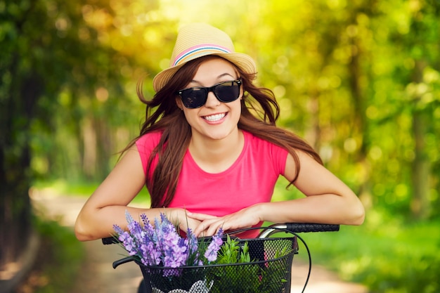 Retrato de uma mulher sorridente andando de bicicleta no parque