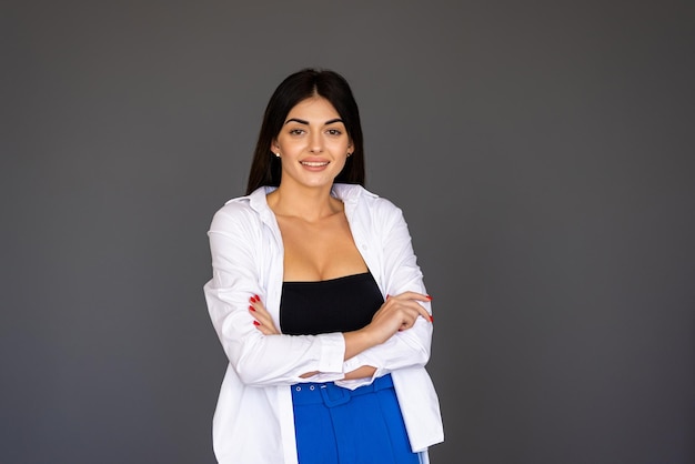 Retrato de uma mulher sorridente com os braços cruzados sobre fundo cinza