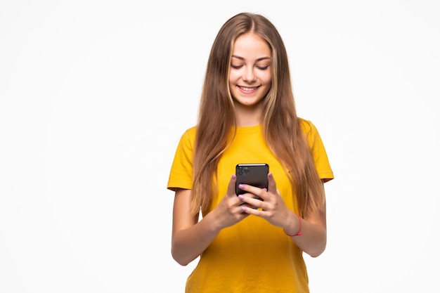 Retrato de uma mulher sorridente e casual segurando o smartphone sobre uma parede branca