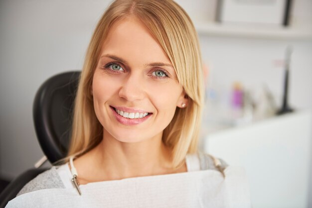 Retrato de uma mulher sorridente e satisfeita na clínica do dentista