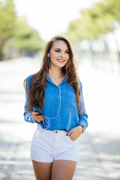 Retrato de uma mulher sorridente feliz em pé na praça no dia ensolarado de verão ou primavera lá fora, linda mulher sorridente olhando para você, jovem atraente aproveitando o verão, imagem filtrada, luz do sol