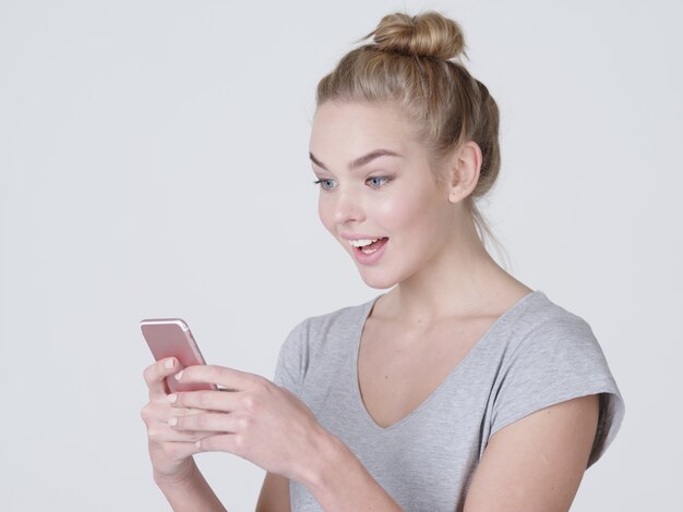 Retrato de uma mulher surpresa com o celular nas mãos - no estúdio