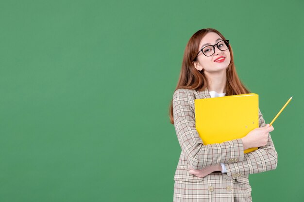 Retrato de uma professora posando com uma lima amarela e um lápis sorrindo alegremente em verde