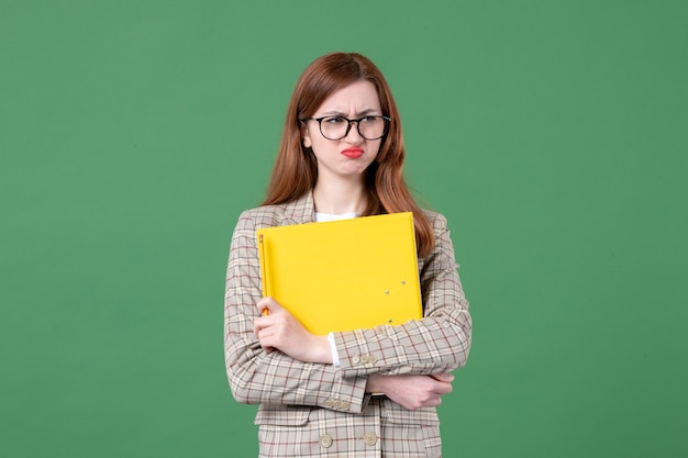 Retrato de uma professora segurando arquivos amarelos em verde