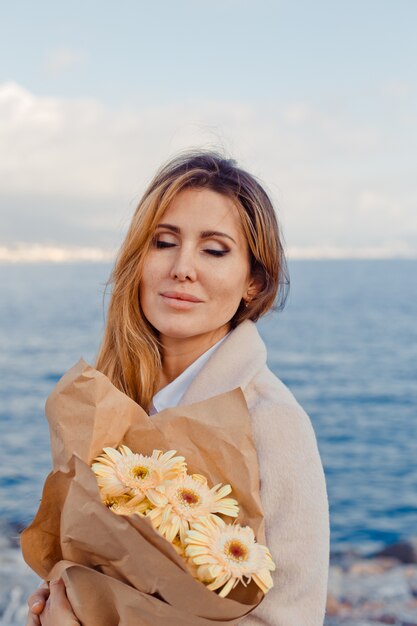 Retrato de uma senhora linda em pé e imaginando algo à beira-mar durante o dia.