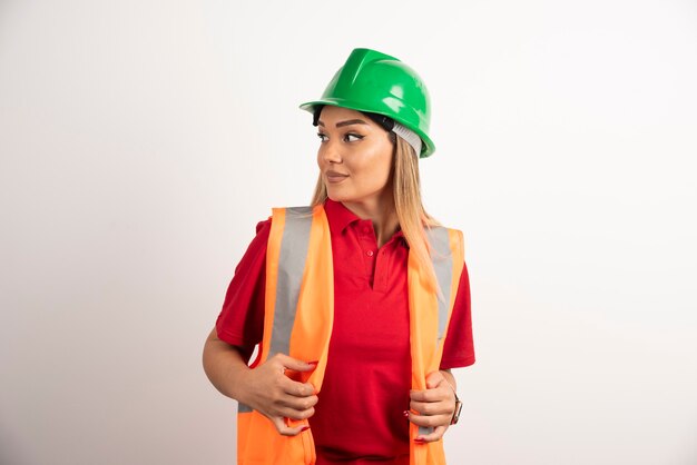 Retrato de uma trabalhadora posando com capacete em fundo branco.