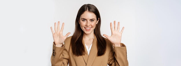 Retrato de vendedora corporativa mostrando os dedos número dez e sorrindo de terno sobre