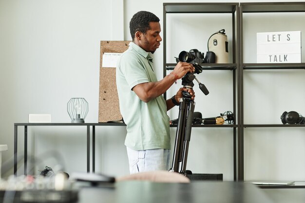 Retrato de vista lateral de homem afro-americano configurando equipamento de gravação no espaço de cópia de estúdio