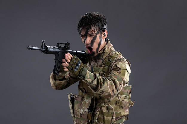 Retrato do bravo soldado camuflado durante a operação na parede escura