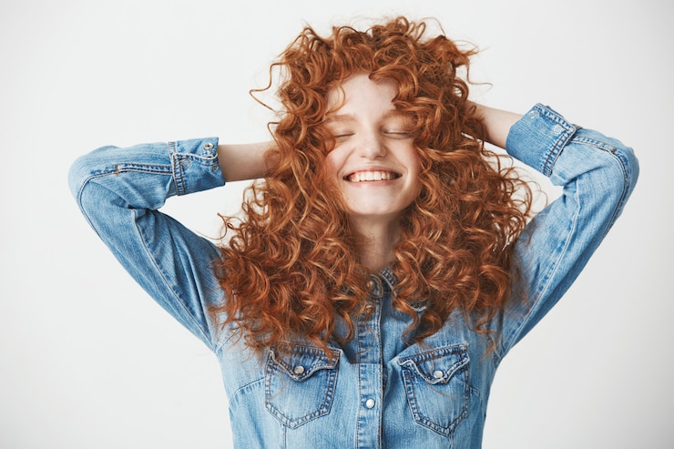 Foto grátis retrato do cabelo tocante da menina bonita foxy que sorri com os olhos fechados sobre o baackground branco.