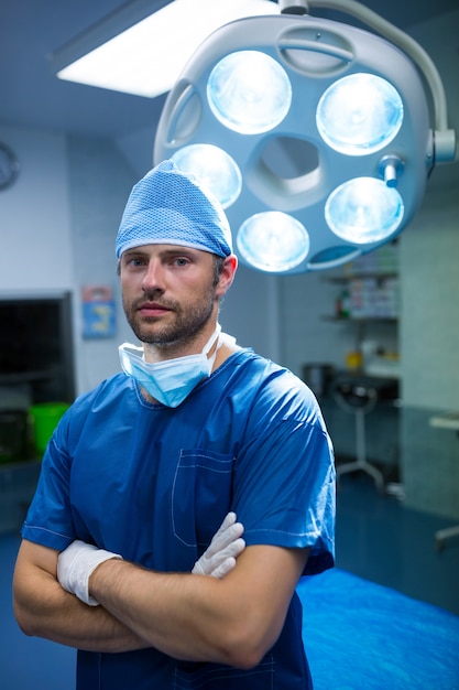 Retrato do cirurgião de pé com os braços cruzados no quarto de operação