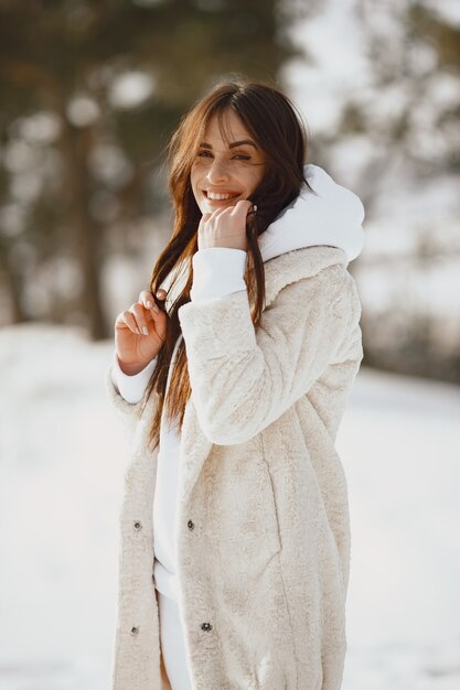 Retrato do close-up de mulher de jaqueta preta. Mulher de pé em uma floresta em um dia de neve.