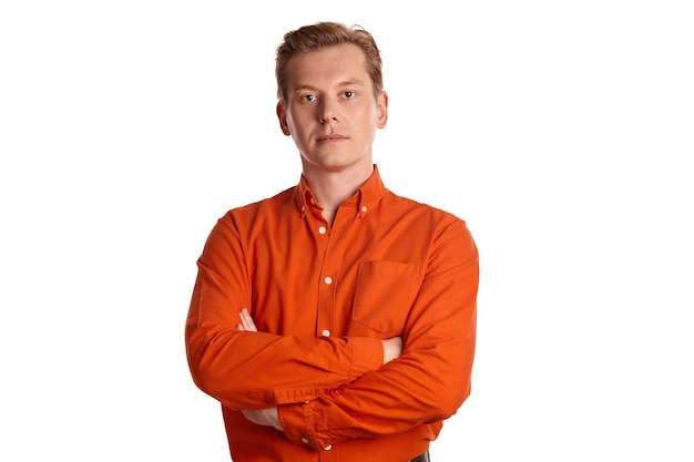 Retrato do close-up de um jovem ruivo bonito em uma elegante camisa laranja, olhando para a câmera e sorrindo enquanto posava isolado no fundo branco do estúdio. expressões faciais humanas. emo sincero