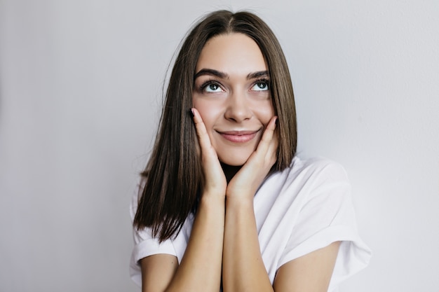 Retrato do close-up de uma linda menina morena, pensando em algo agradável. modelo feminino encantador olhando com um sorriso sonhador.