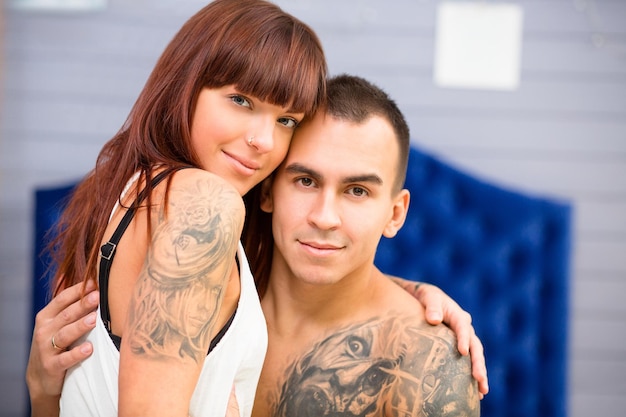 Retrato do close-up do jovem casal sentado na cama e olhando para a câmera. Feliz homem e mulher, passando a lua de mel no hotel.