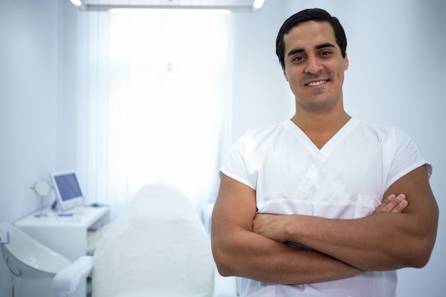 Retrato do dentista masculino em pé com os braços cruzados