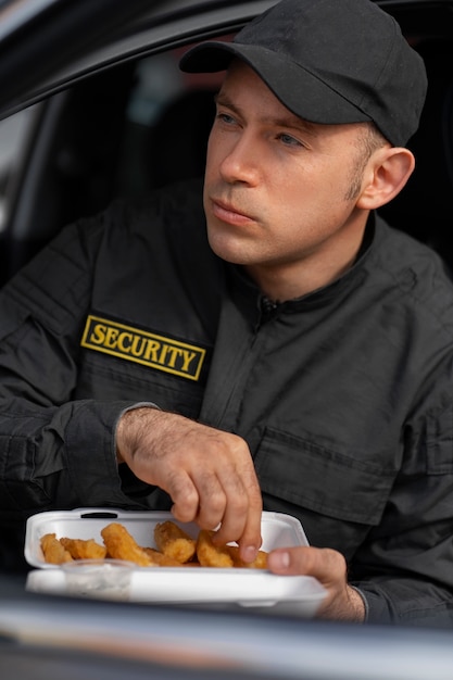 Retrato do guarda de segurança masculino tendo uma pausa para o almoço