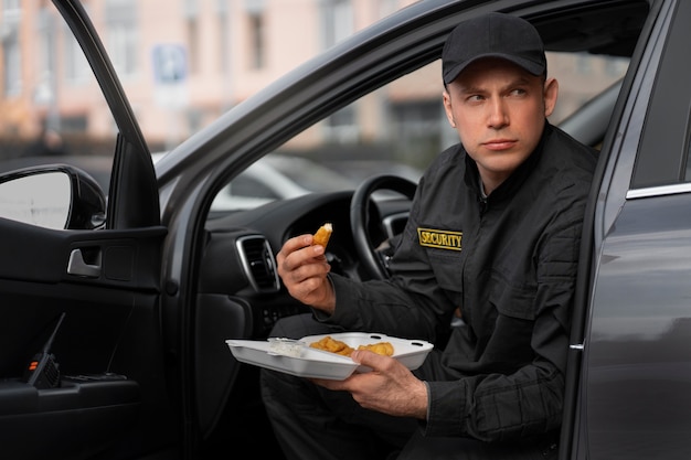 Retrato do guarda de segurança masculino tendo uma pausa para o almoço