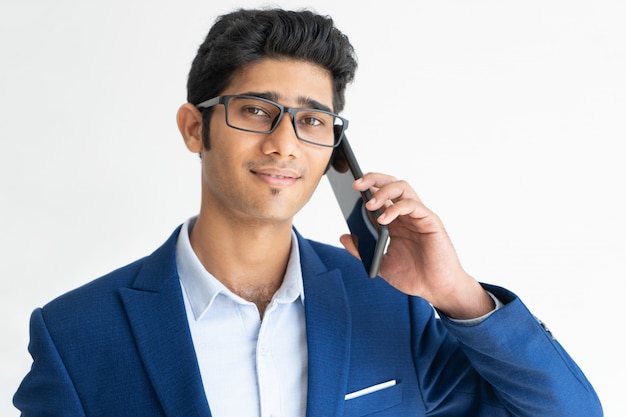 Retrato do homem de negócios de sorriso nos vidros que fala no smartphone.