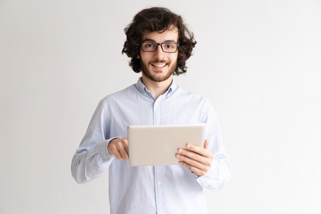 Retrato do homem de negócios novo de sorriso que trabalha na tabuleta digital.