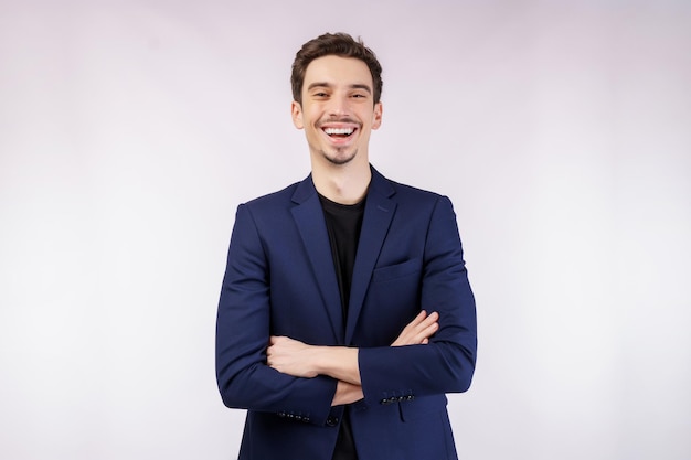 Foto grátis retrato do jovem empresário bonito vestindo terno em pé com os braços cruzados com isolado no fundo branco do estúdio