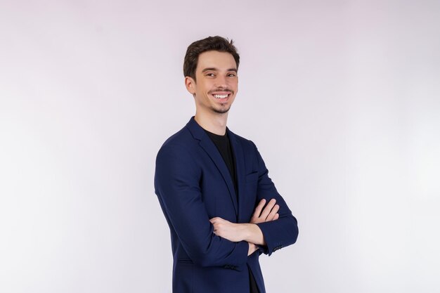 Retrato do jovem empresário bonito vestindo terno em pé com os braços cruzados com isolado no fundo branco do estúdio