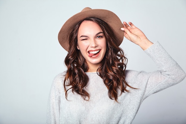 Retrato do jovem modelo rindo elegante em roupas de verão casual cinza com chapéu marrom com maquiagem natural