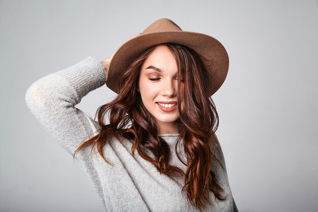 Retrato do jovem modelo rindo elegante em roupas de verão casual cinza com chapéu marrom com maquiagem natural