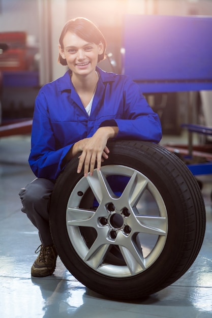 Retrato do mecânico fêmea com um pneu