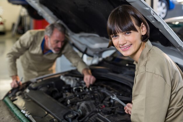 Retrato do mecânico fêmea que examina motor de carro