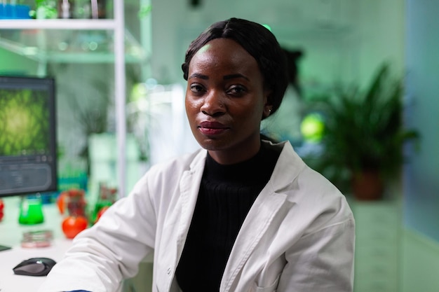 Retrato do médico científico do botânico americano africano, olhando para a câmera durante o experimento de robiologia, analisando o teste genético. equipe multiétnica trabalhando em laboratório de hospital biológico
