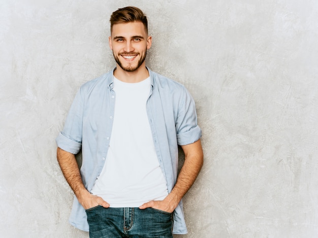 Retrato do modelo bonito jovem sorridente, vestindo roupas de camisa casual. Moda elegante homem posando