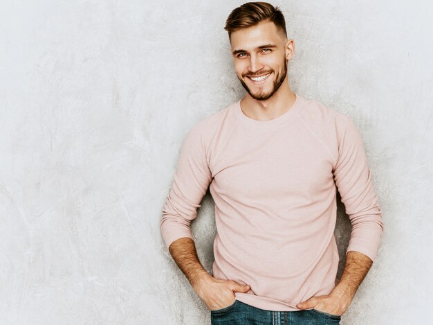 Retrato do modelo bonito jovem sorridente, vestindo roupas de verão casual rosa. Moda elegante homem posando