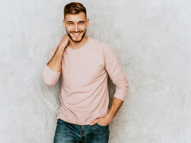 Retrato do modelo bonito jovem sorridente, vestindo roupas de verão casual rosa. Moda elegante homem posando